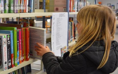 bambina che prende un libro in biblioteca