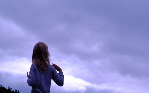 bambina di spalle che osserva il cielo