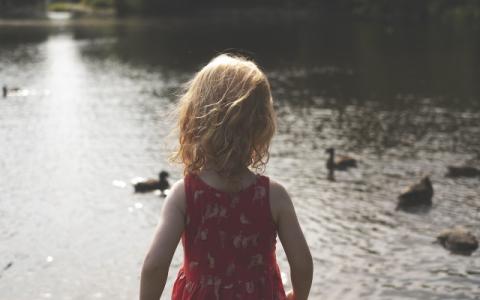 bambina di spalle che osserva un lago