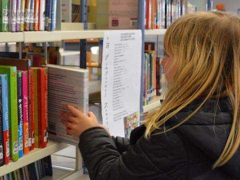 bambina che prende un libro in biblioteca