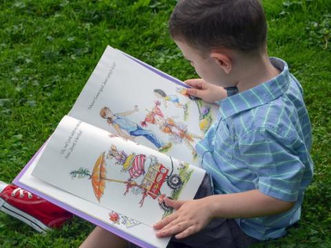 immagine di bambino che legge un libro per evocare il tema della promozione della lettura nella prima infanzia