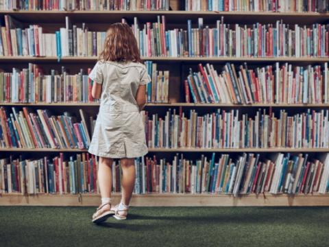 bambina che consulta libri in biblioteca
