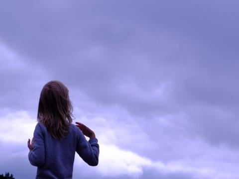 bambina di spalle che osserva il cielo