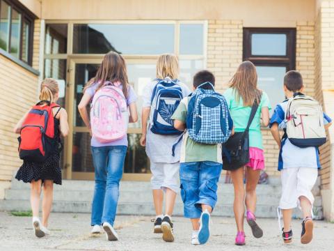 bambini di spalle che entrano a scuola 